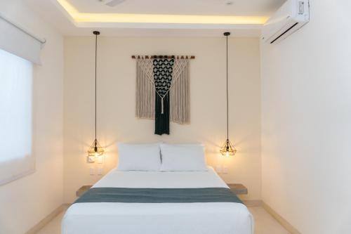 a bedroom with a white bed and two lights at Kanté Hotel - Downtown Tulum in Tulum