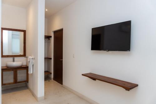 a bathroom with a television on a wall at Kanté Hotel - Downtown Tulum in Tulum
