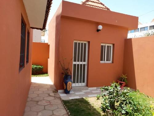 an orange house with a white door and a yard at Chambre Orange in Mbour