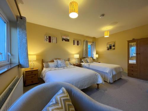 a bedroom with two beds and two windows at PK Lodge B&B in Skibbereen
