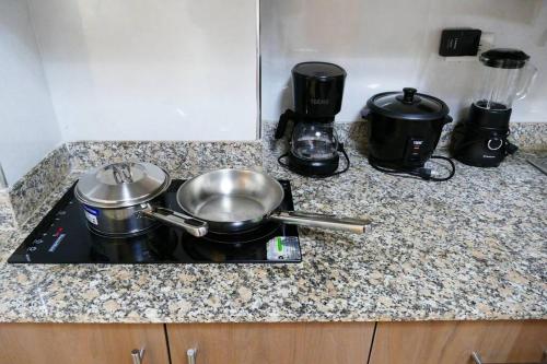 a stove top with pots and pans on a counter at Ecusuites Penthouse Vía Costa Ceibos Puerto Azul in Guayaquil