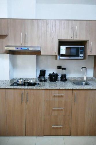 a kitchen with a stove and a microwave and a sink at Ecusuites Penthouse Vía Costa Ceibos Puerto Azul in Guayaquil