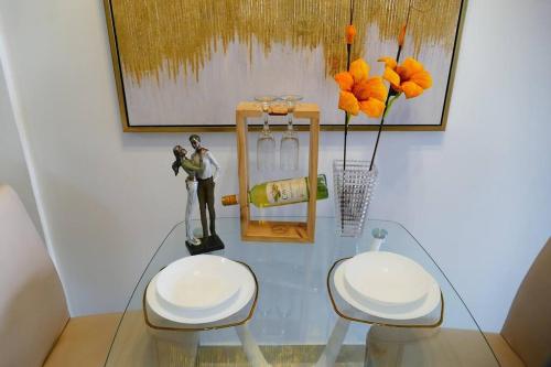 a glass table with two white chairs and flowers at Ecusuites Penthouse Vía Costa Ceibos Puerto Azul in Guayaquil
