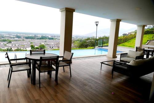 a living room with a table and chairs and a pool at Ecusuites Penthouse Vía Costa Ceibos Puerto Azul in Guayaquil