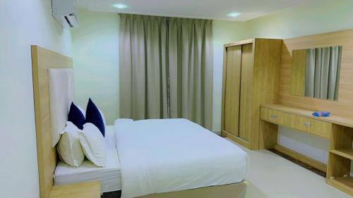 1 dormitorio con cama blanca y almohadas azules en بولاريس فيو en Yeda