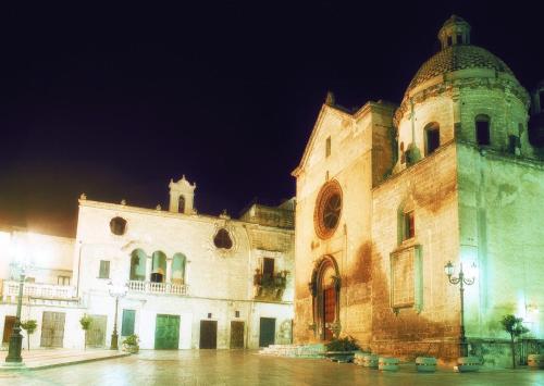 a large building with a clock tower at night at La Valle delle Rose in Massafra