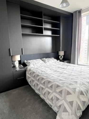 ein Schlafzimmer mit einem Bett mit einer weißen Bettdecke in der Unterkunft Bright Modern Flat with Balcony 30mins from Euston in Harrow