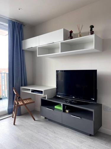 ein Wohnzimmer mit einem Flachbild-TV auf einem Entertainment-Center in der Unterkunft Bright Modern Flat with Balcony 30mins from Euston in Harrow