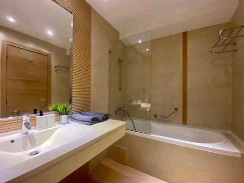 ein Badezimmer mit einer Badewanne, einem Waschbecken, einer Badewanne und einem Spiegel in der Unterkunft ApartHotel RIN Grand Residence in Bukarest