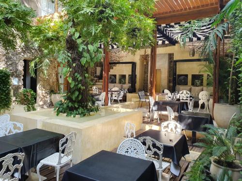 restauracja ze stołami, krzesłami i drzewem w obiekcie Hotel Casa Lola Deluxe Gallery w mieście Cartagena de Indias