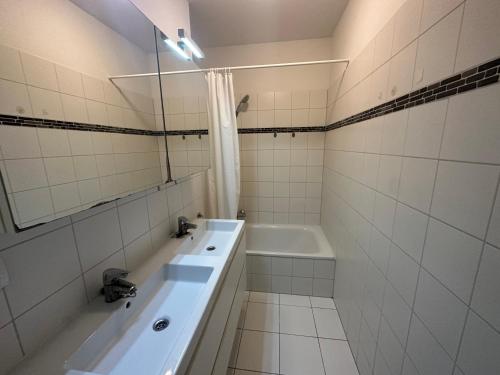 Baño de azulejos blancos con lavabo y bañera en 2 Bedroom Apartment in Center with Balcony, en Bruselas