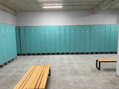 a locker room with green lockers and a wooden bench at Hotel Peak in Gudauri