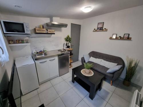 eine Küche und ein Wohnzimmer mit einem Sofa und einem Tisch in der Unterkunft Agréable Logement / Netflix in Saint-Pierre-des-Corps