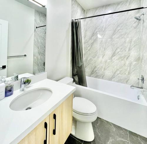 a bathroom with a sink and a toilet and a tub at Family Friendly Ground Level Condo in Surrey