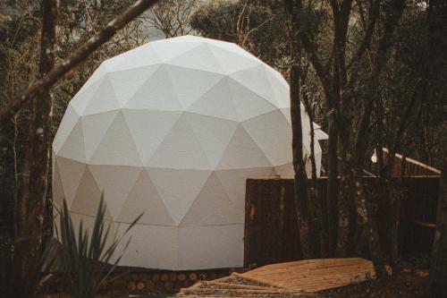 a large white orb in the middle of a forest at Domo Supernova by @highlowstays in Gramado