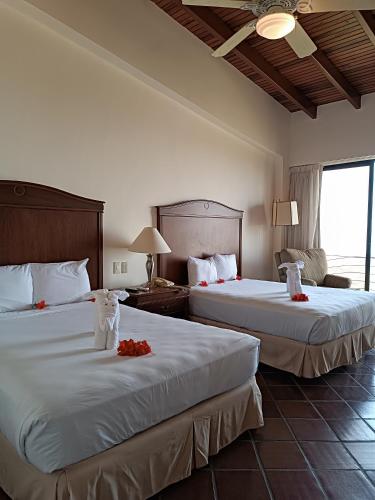 a hotel room with two beds with red flowers on them at Hotel Eco Inn Jose in Puerto Píritu