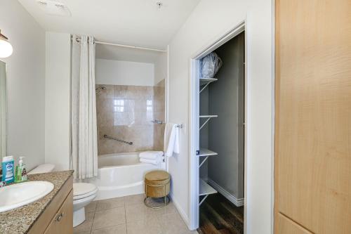 a bathroom with a tub and a toilet and a sink at Luxe Long Beach Condo with Pool 1 Mi to Shoreline! in Long Beach