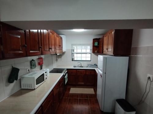 cocina con armarios de madera y nevera blanca en Casa das Palmeiras, en Lajes das Flores