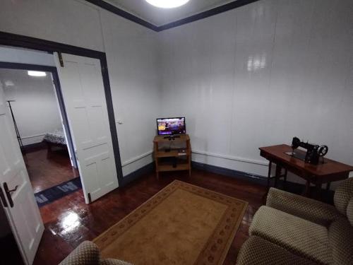 een woonkamer met een televisie en een tafel met stoelen bij Casa das Palmeiras in Lajes das Flores