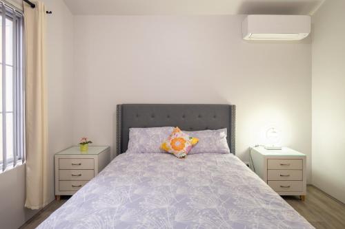 ein Schlafzimmer mit einem Bett und zwei Nachttischen in der Unterkunft West Swan B&B in Perth