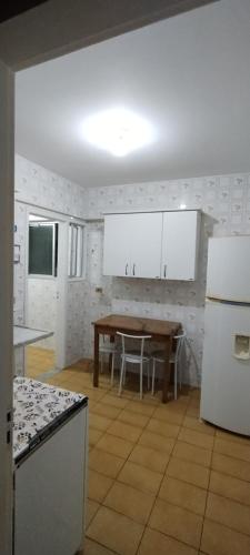 una cocina con armarios blancos y una mesa. en Apartamento Guarapari, en Guarapari