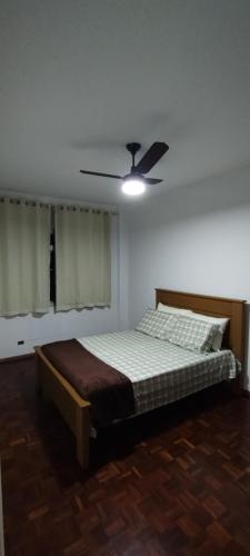 1 dormitorio con 1 cama y ventilador de techo en Apartamento Guarapari, en Guarapari