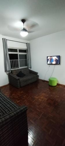 sala de estar con sofá y TV en Apartamento Guarapari, en Guarapari