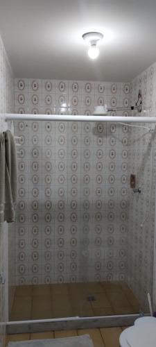 baño con ducha y puerta de cristal en Apartamento Guarapari, en Guarapari