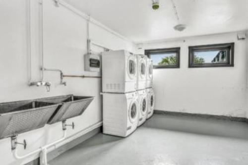 a laundry room with three washing machines and sinks at Trivelig studioleilighet på byåsen med treningsrom, uteareal og parkering in Trondheim