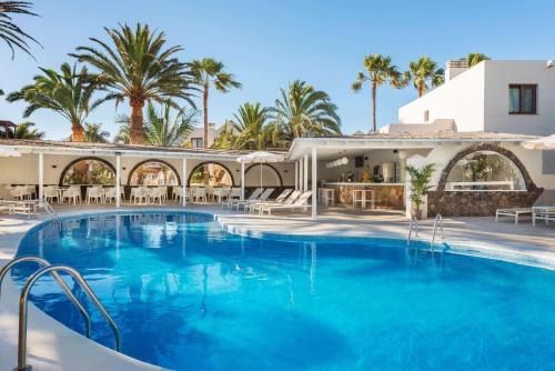 a large swimming pool in a resort with palm trees at Alua Suites Fuerteventura - All Inclusive in Corralejo