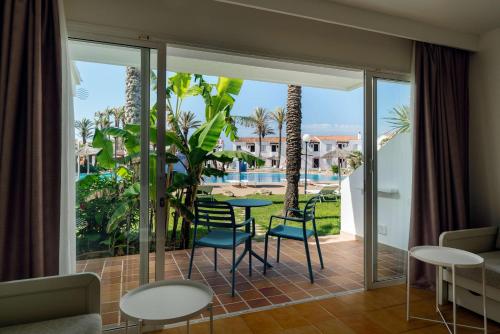 Habitación con balcón con mesa y sillas. en AluaSun Mediterráneo en S'Algar