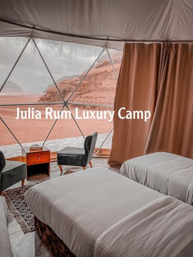 two beds in a room with a view of the desert at Julia Rum Luxury Camp in Wadi Rum