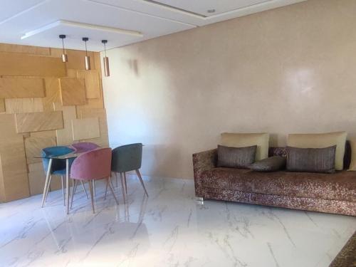 a living room with a couch and a table and chairs at Tayyurt Surf Camp Tamraght Aourir in Awrir