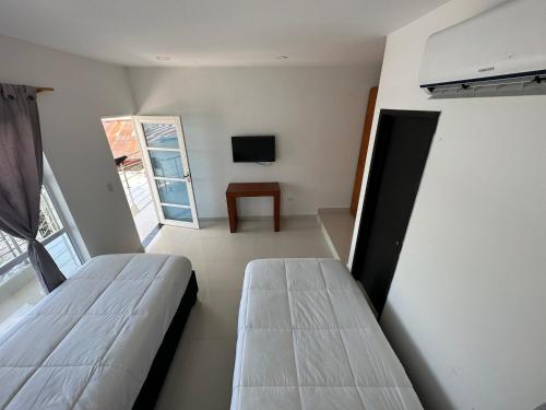 a small room with two beds and a television at Rio-ApartaHotel-Lagos in Leticia