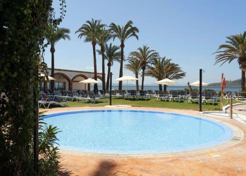 una piscina con palmeras y sillas en AluaSun Doblemar, en La Manga del Mar Menor