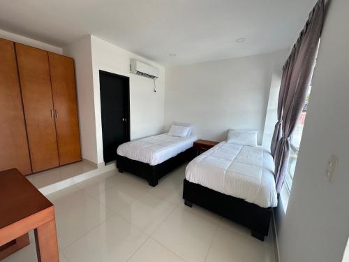 a hotel room with two beds and a desk at Rio-ApartaHotel-Lagos in Leticia