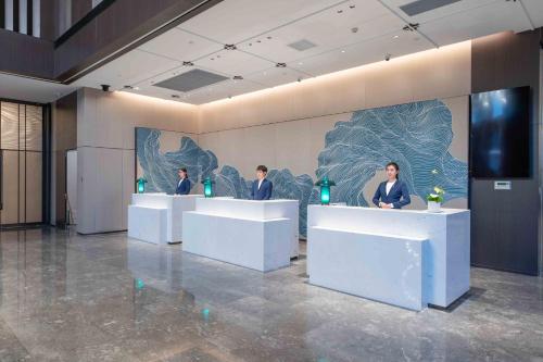 a group of people standing at reception desks in a lobby at Holiday Inn Taiyuan Sunshine by IHG in Taiyuan