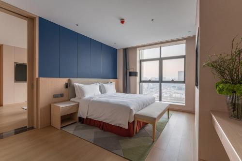 a bedroom with a large bed with a blue wall at Holiday Inn Taiyuan Sunshine by IHG in Taiyuan