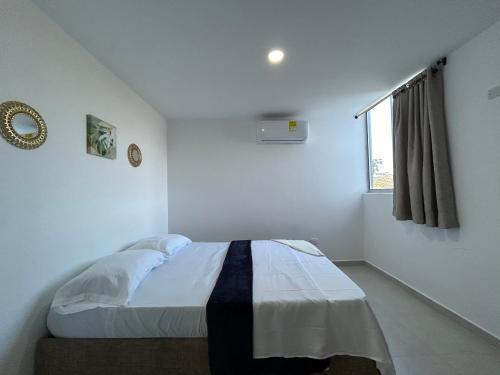 een witte slaapkamer met een bed en een raam bij Apartamento Coveñas in Coveñas