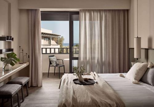 ein Hotelzimmer mit einem Bett und einem Balkon in der Unterkunft Numo Ierapetra Beach Resort Crete, Curio Collection Hilton in Ierápetra