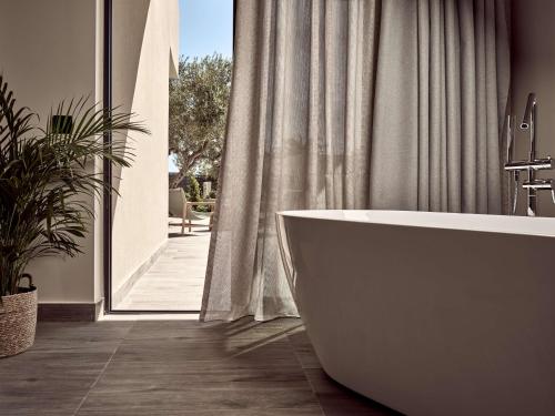 a bathroom with a tub and a large window at Numo Ierapetra Beach Resort Crete, Curio Collection Hilton in Ierápetra