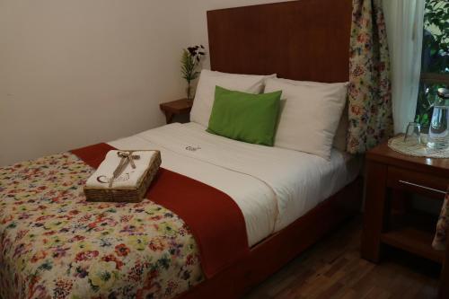 a bed with a green pillow and a purse on it at Chalet del Carmen, Coyoacán in Mexico City