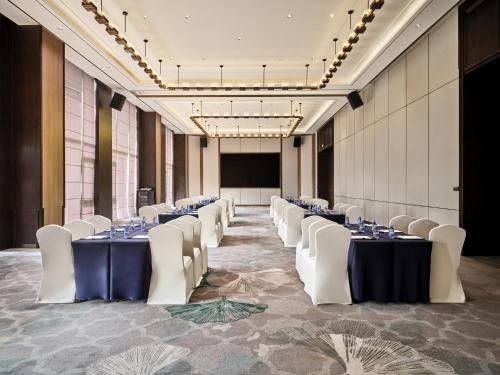 a conference room with tables and white chairs and a screen at Crowne Plaza Chengdu Wuhou by IHG in Chengdu