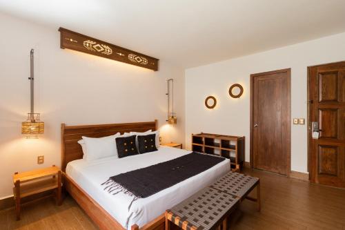 Un dormitorio con una cama grande y un banco. en Sombra del Agua, en San Cristóbal de Las Casas