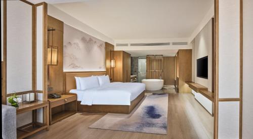 a bedroom with a bed and a tub and a television at Crowne Plaza Chengdu Wuhou by IHG in Chengdu