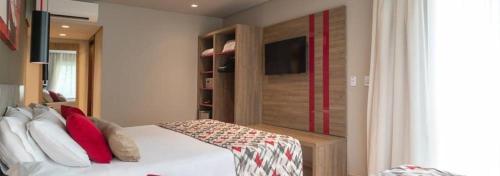 a bedroom with a white bed with red pillows at Laghetto Stilo Borges - Apto 403B in Gramado