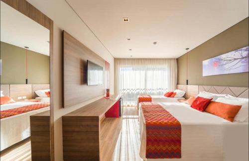 um quarto de hotel com duas camas e uma televisão em Laghetto Stilo Borges - Apto 403B em Gramado