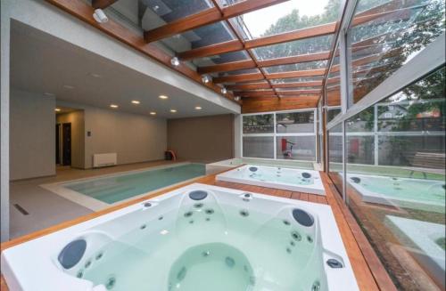a large bathroom with two hot tubs and a swimming pool at Laghetto Stilo Borges - Apto 403B in Gramado