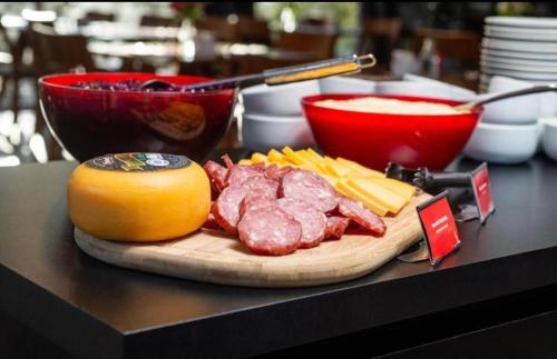 a cutting board with meat and cheese on a table at Laghetto Stilo Borges - Apto 403B in Gramado
