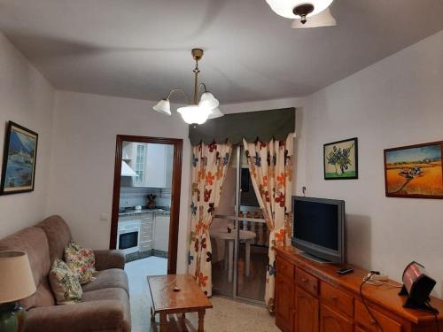 a living room with a couch and a television at Mi bonito apartamento del Portil in El Portil